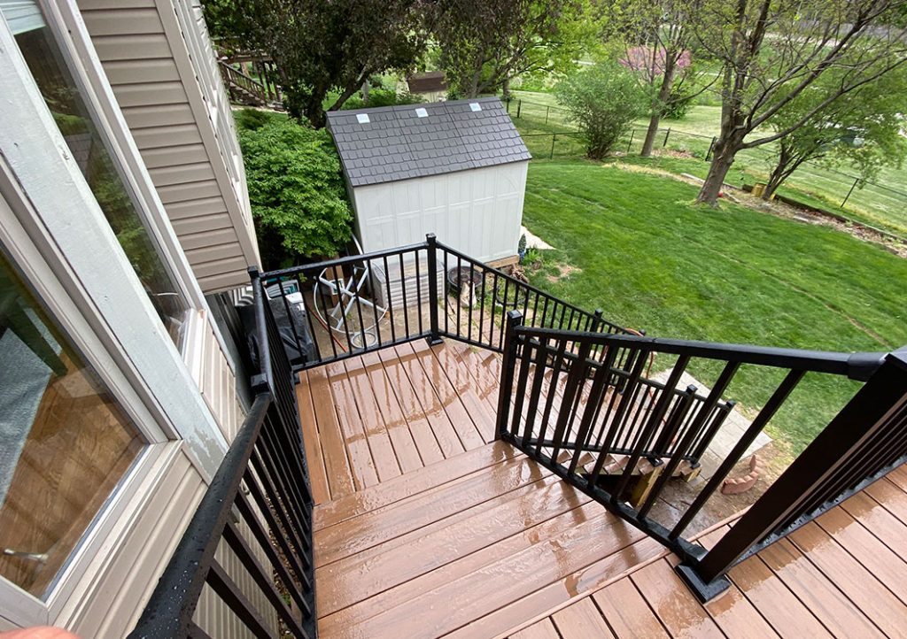 Rainy day view of composite stairs set with black metal railings.