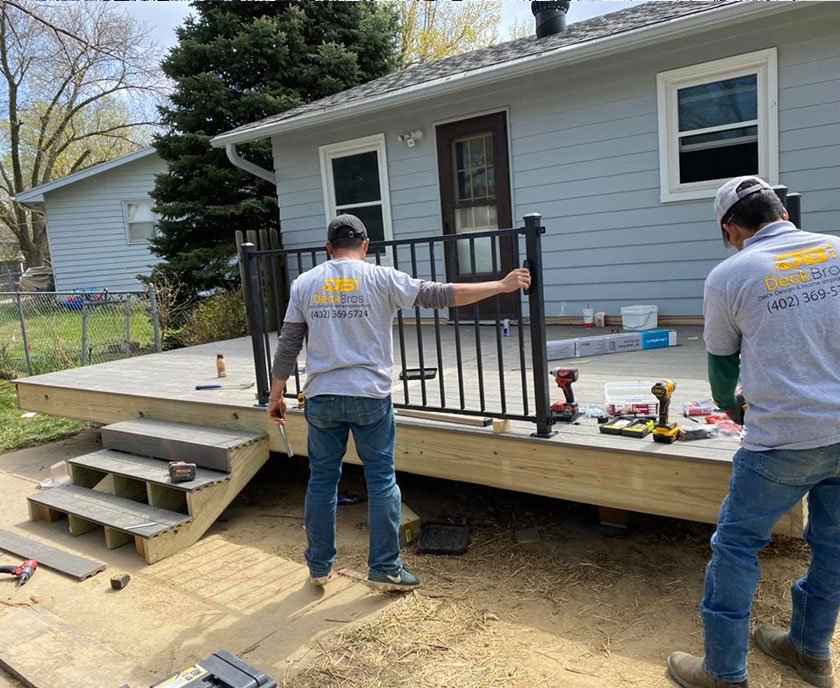 Process page demonstration image depicting Deck Bros workers installing a railing on a wooden deck