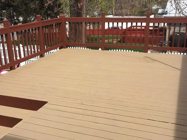 A deck with reddish brown railing