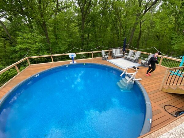 A wood deck with a pool and a woman