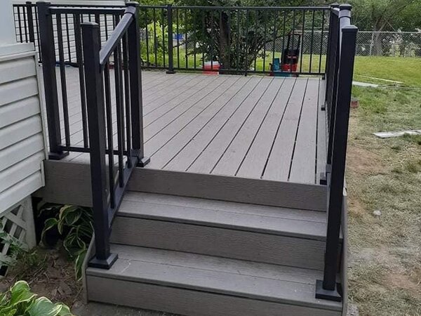 A small deck with three steps and a metal railing