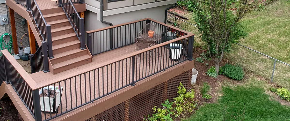 A two level deck with railings and a patch of grass