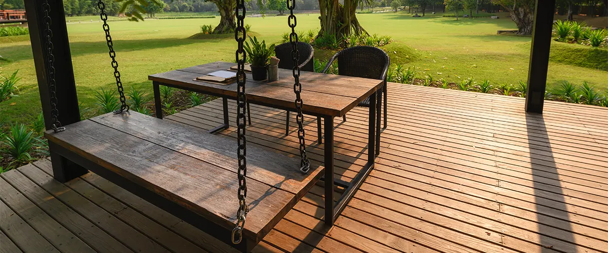 A deck addition cost with a swinger and a table on a patch of grass