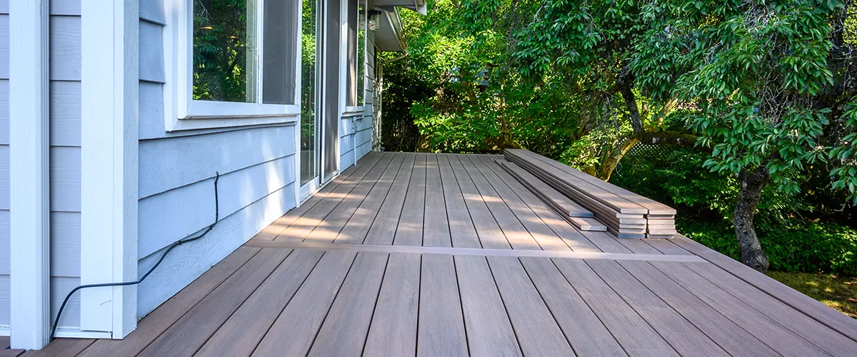 A brown decking with light gray home siding and several boards stacked
