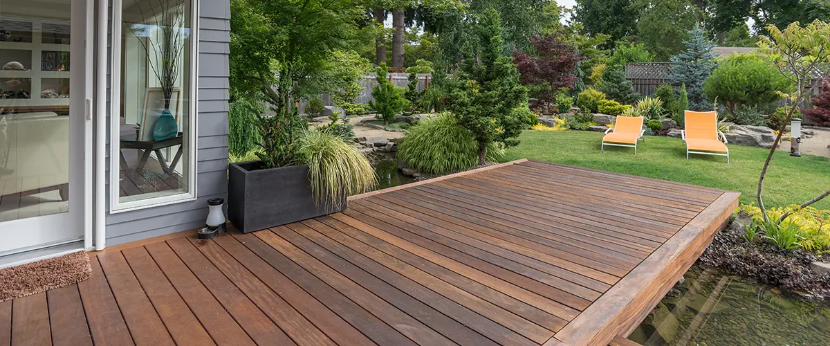 A dark composite deck near a pond with many plants