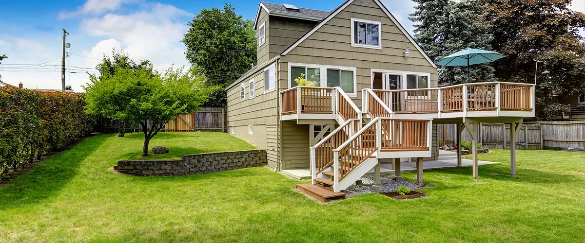 An elevated deck with stairs and a big lawn