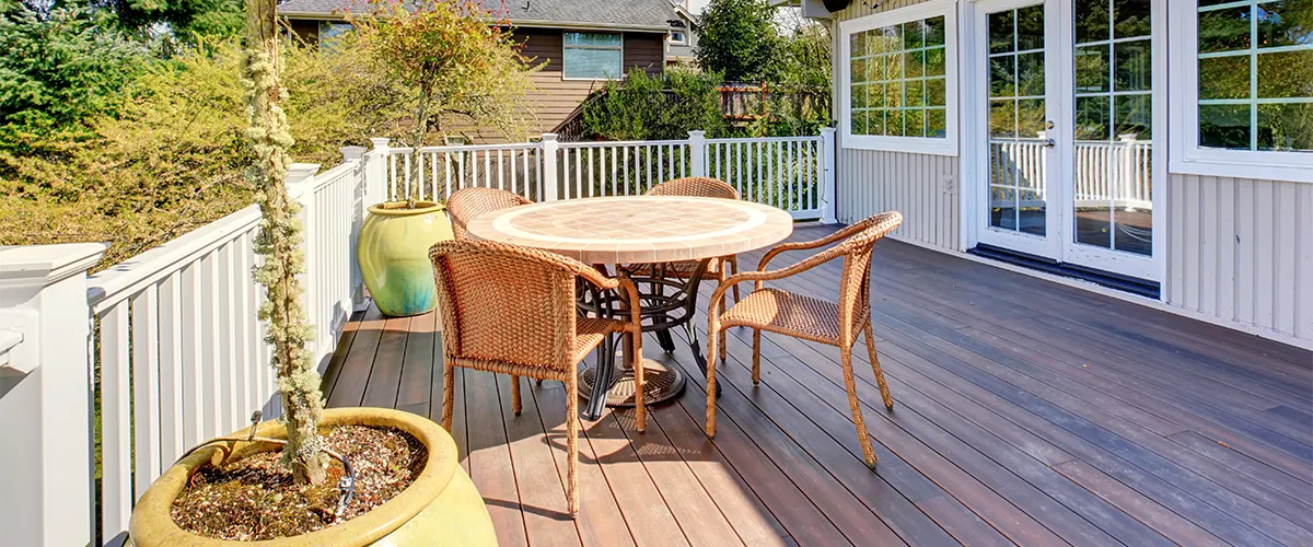 A brown composite deck with a round table and chairs