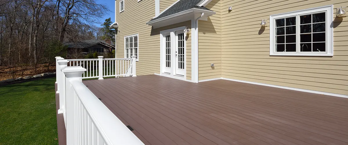 An empty deck surface with white railings and brown deck boards