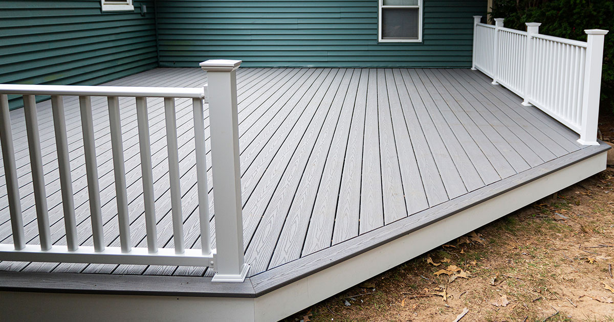 A gray composite decking with a green home siding