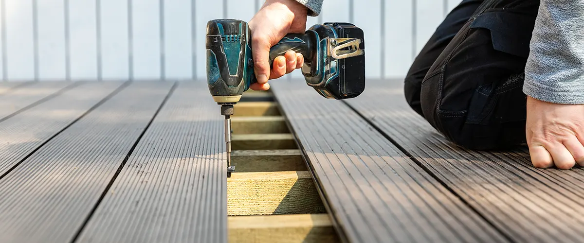 A man using a screwdriver to install decking boards