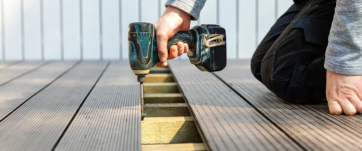 The best deck builder working with a screwdriver to fasten decking boards