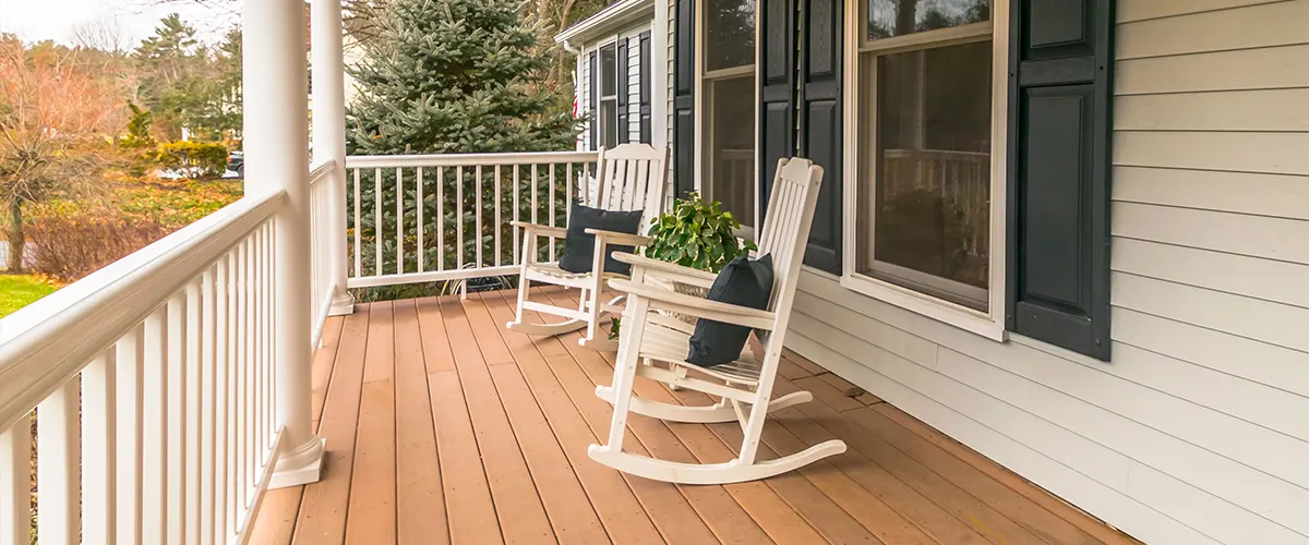 Two white rocking chairs on a deck with white railings