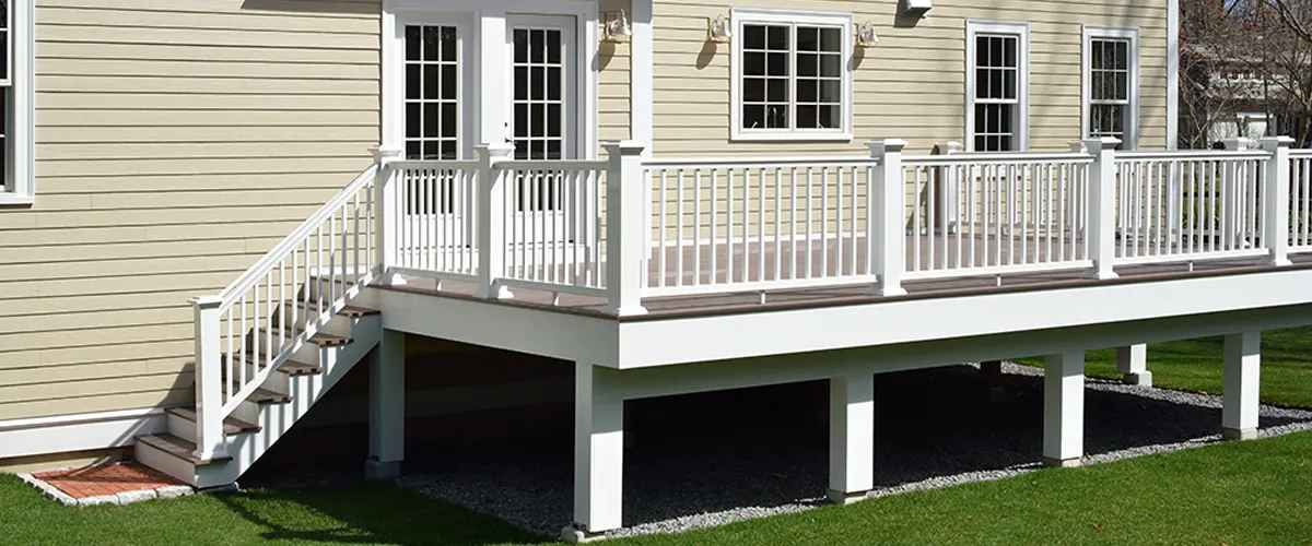 An elevated wood deck with white railing and posts