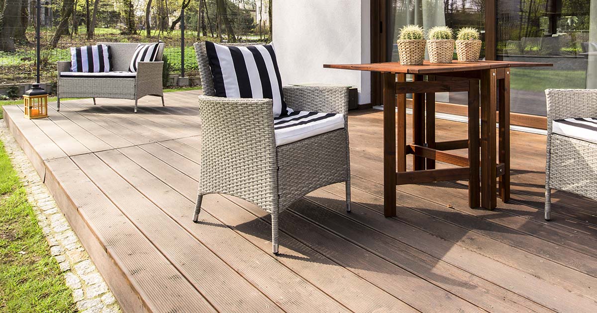 A backyard deck with white chairs and wooden table