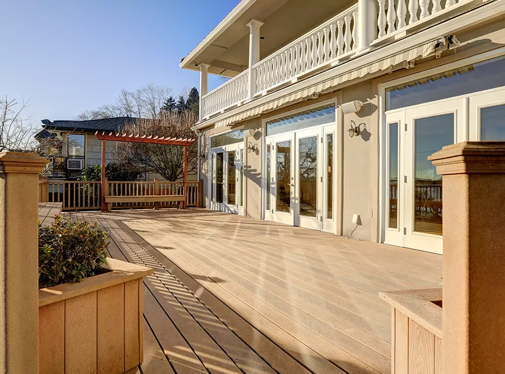 A composite deck with composite railing and a house with large glass doors