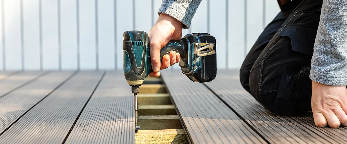 A contractor screwing down composite deck boards