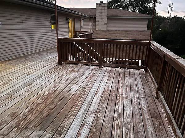 An older wood deck with faded color and a wood rail