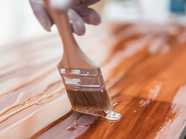 man with brush staining wood