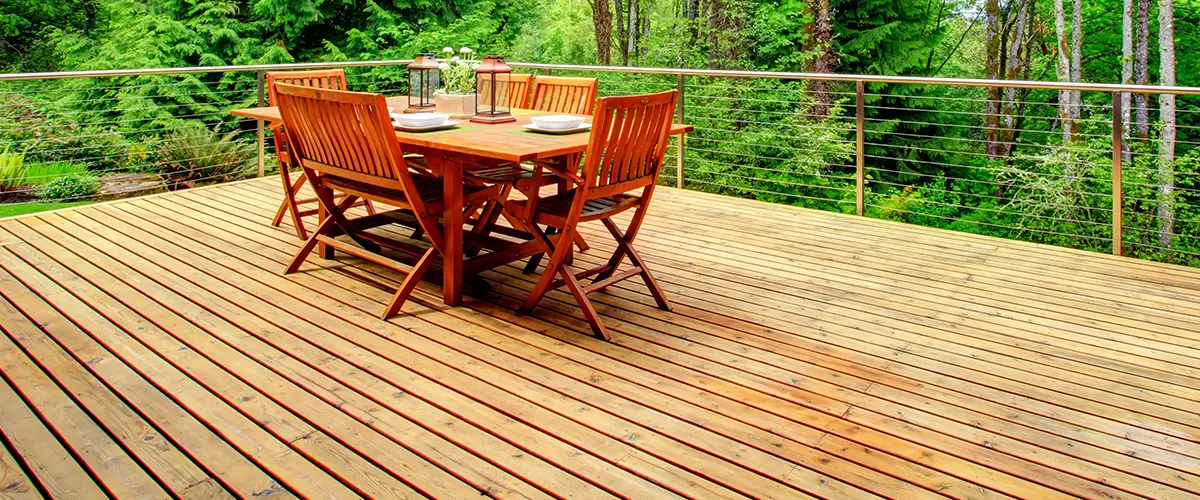 A large wood deck with a wood table and chairs