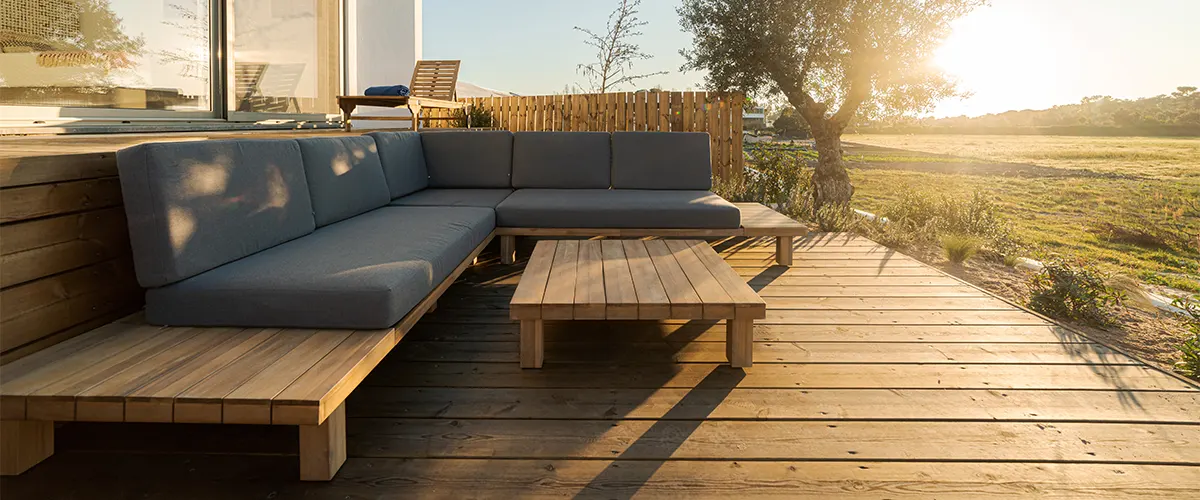 A ground level wood deck with a bench and the sunset behind it