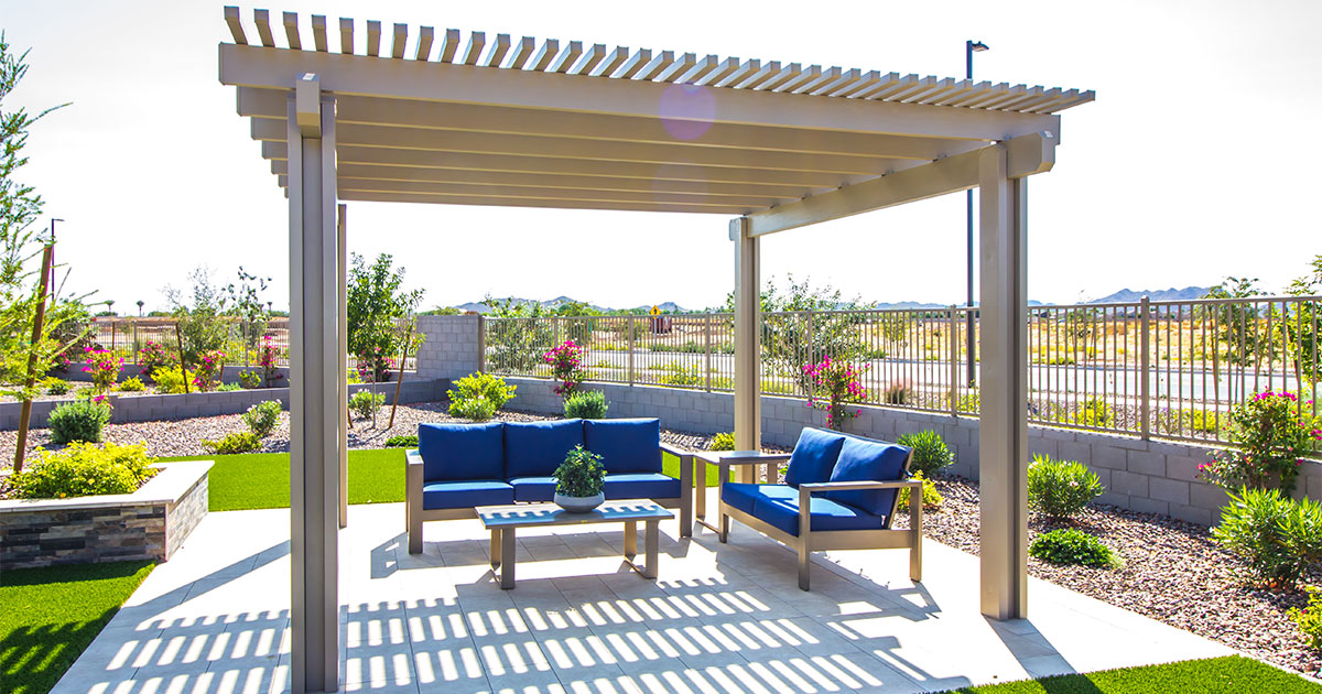 A small pergola in a backyard with two blue benches