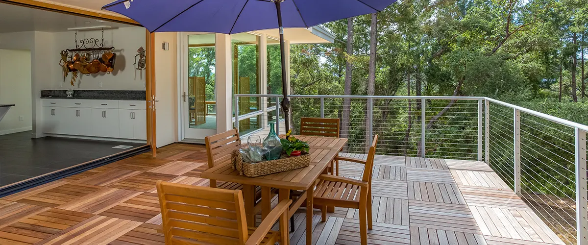 A steel rail on a wood deck with a blue umbrella