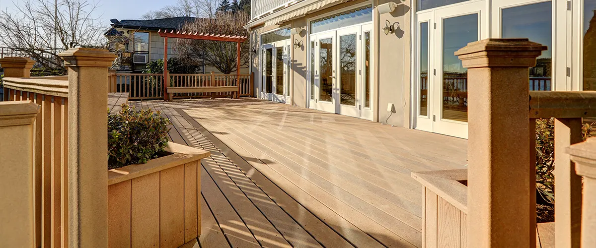 A composite deck with composite railing and posts on the side of a beige home