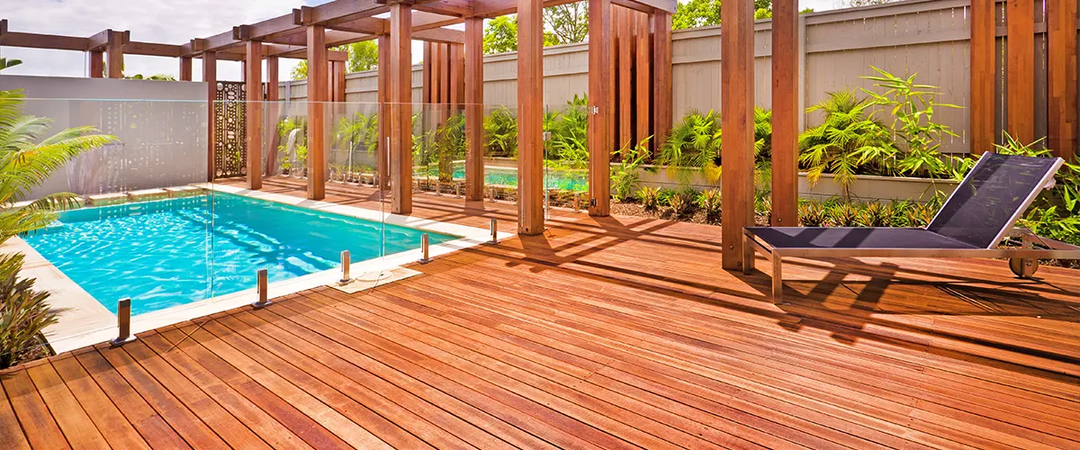 A stained deck with a pool and a long chair