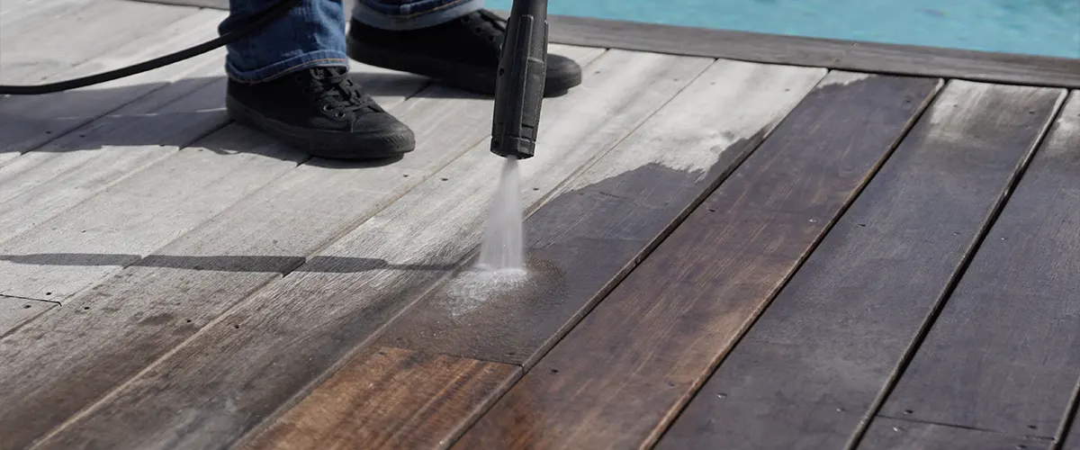 A man pressure washing a deck