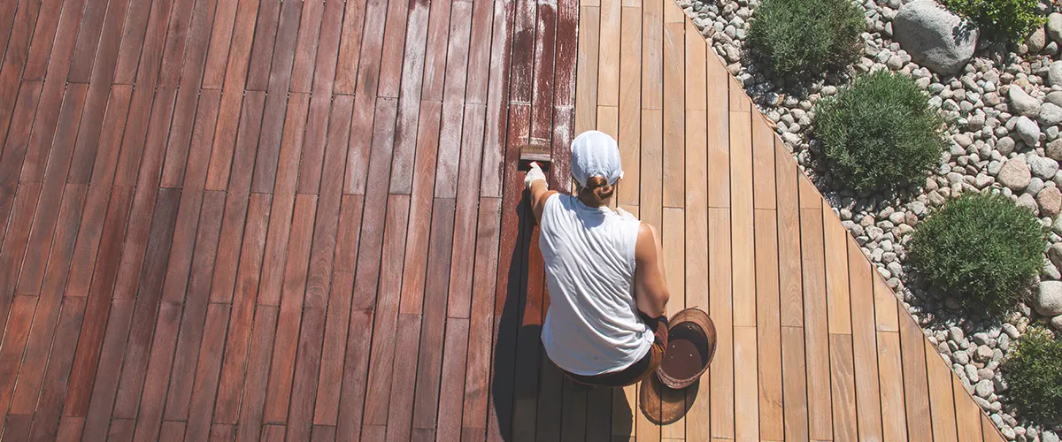 A woman in a white t-shirt painting a deck