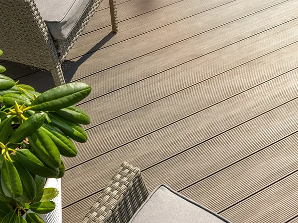 A composite deck in a beige color with a plant and two chairs