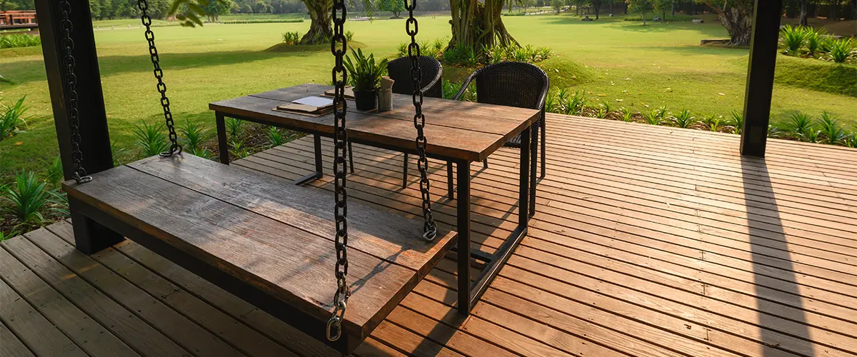 Free standing composite decking with table and chairs on a large patch of grass