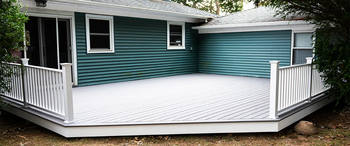 A composite deck with white composite railing on a house with blue siding