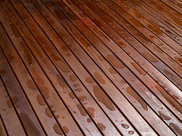A mahogany type of wood with water droplets on its surface