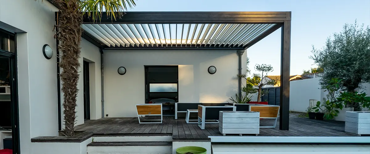 A black pergola on a black deck with white accents on benches