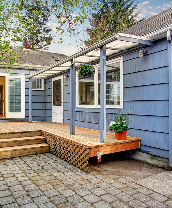 A rather old awning on a home with blue siding