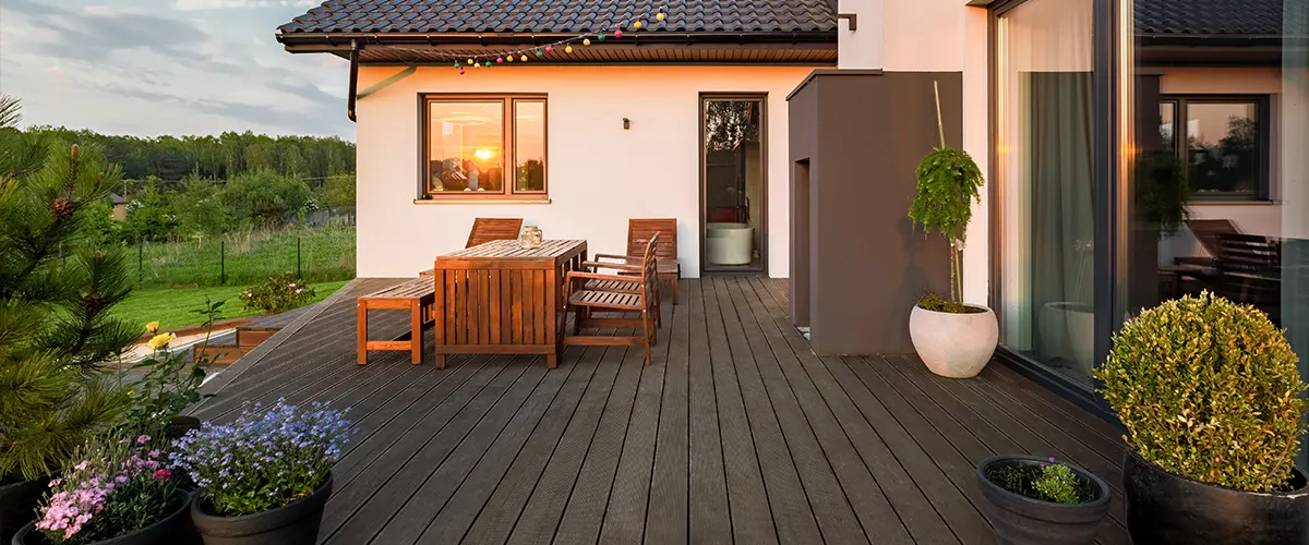 Composite decking with a darker color on a beige home with flowers