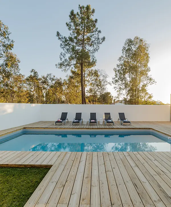 An unfinished pool deck with long chairs and a patch of grass