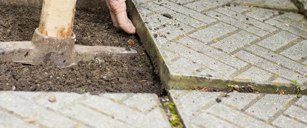 A man trying to remove concrete slabs with a pickaxe