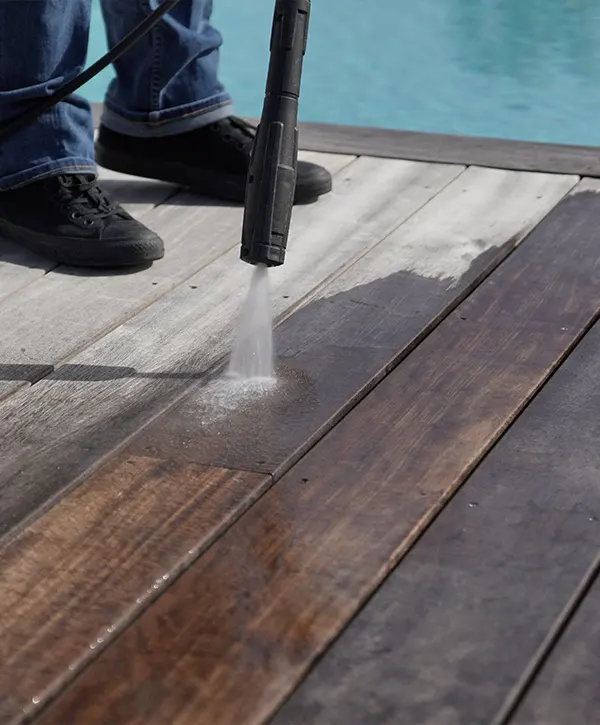 A man power washing a wood deck