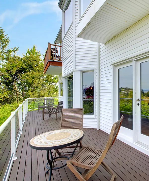 A stained wood deck on the side of a white home