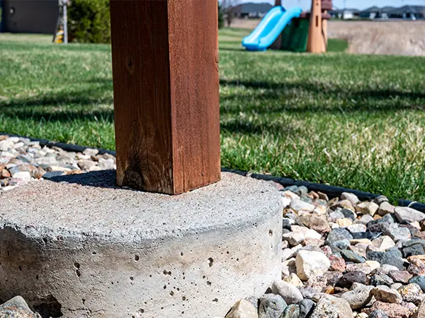A concrete footing and a wood post on it