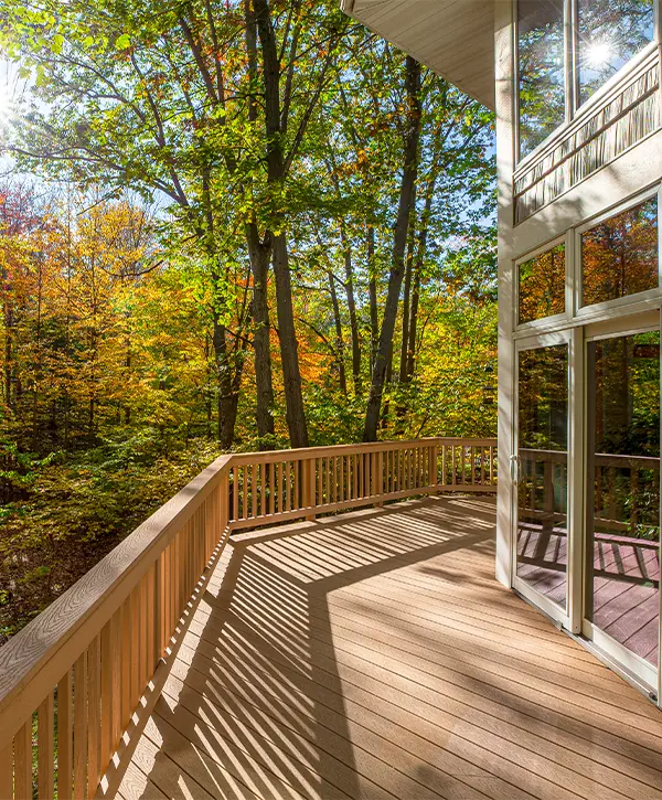 A composite decking attached to a home with large windows and glass doors