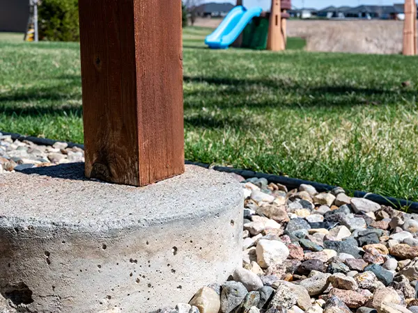 A concrete footing and a wood post