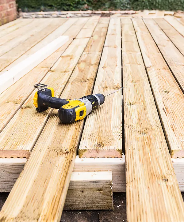 Pressure treated wood and a screwdriver for a deck repair project