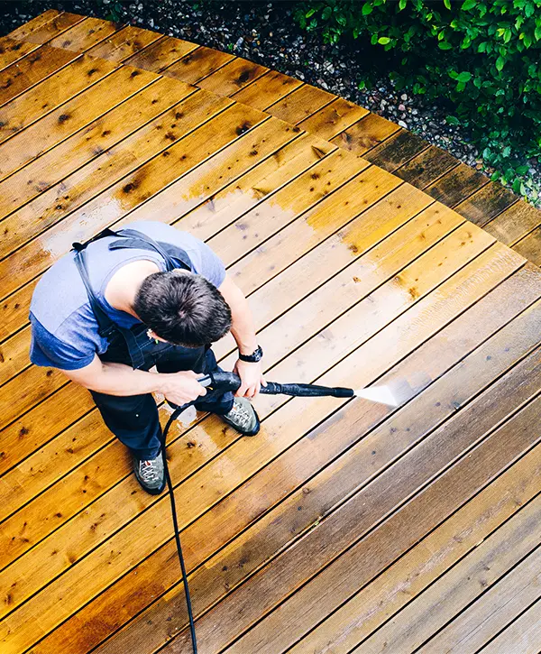 A man pressure washing a wood deck