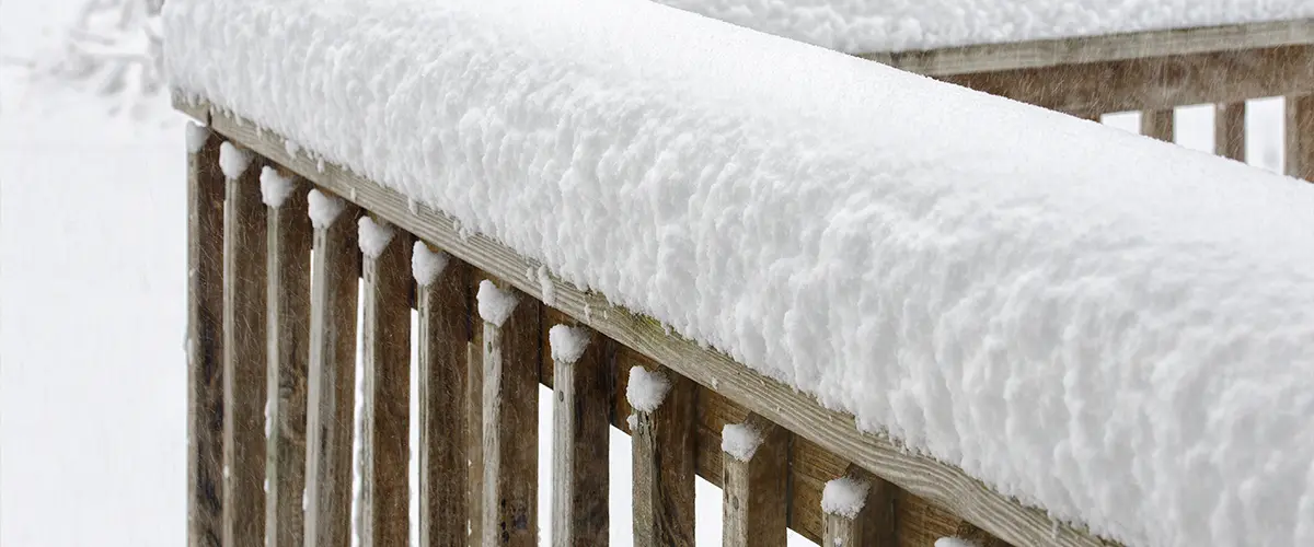 A lot of snow piled up on a deck railing