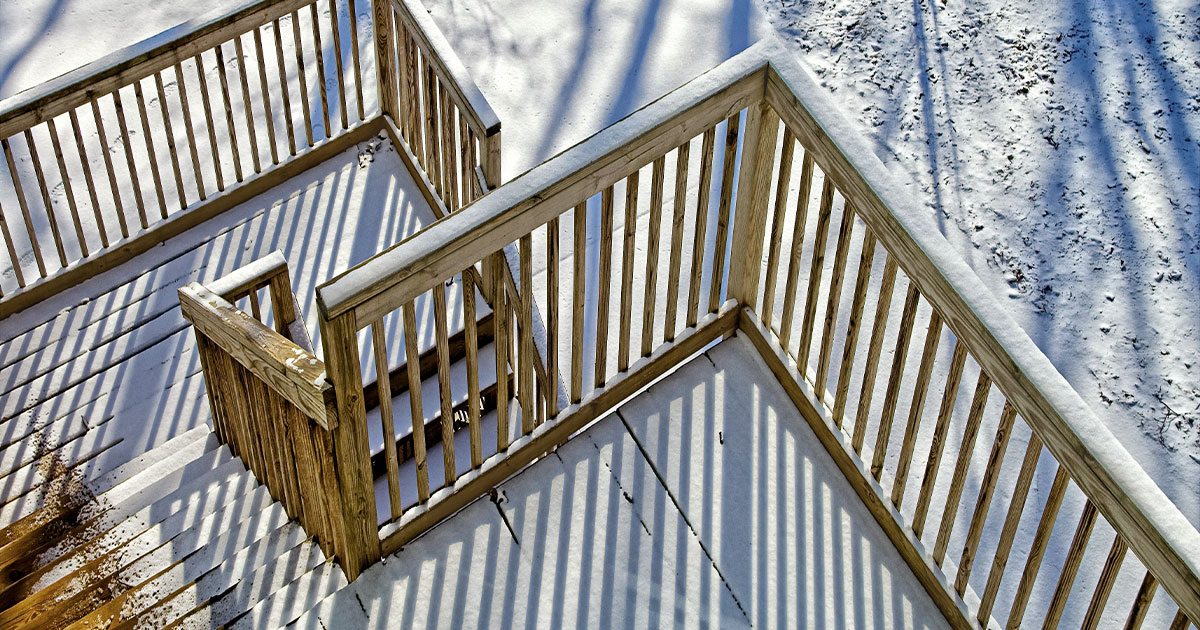 A three-level deck with two sets of stairs covered in melting snow