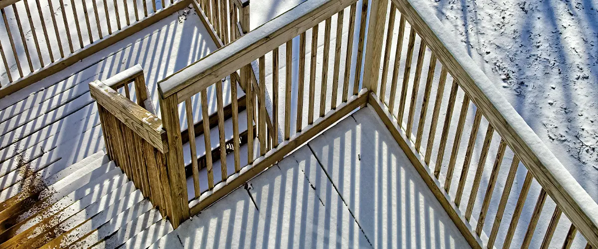 A three-level deck with two sets of stairs covered in melting snow