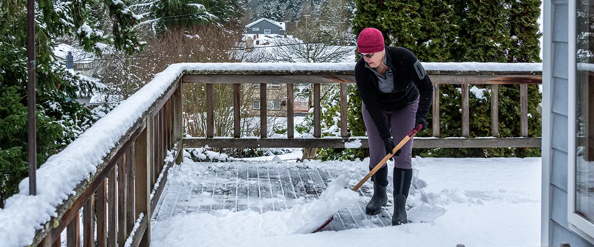 A woman ready to prepare a deck for winter by shoveling snow